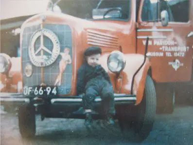 Historische foto van een jongen zittend op de motorkap van een vintage vrachtwagen van Van Paridon Transport.