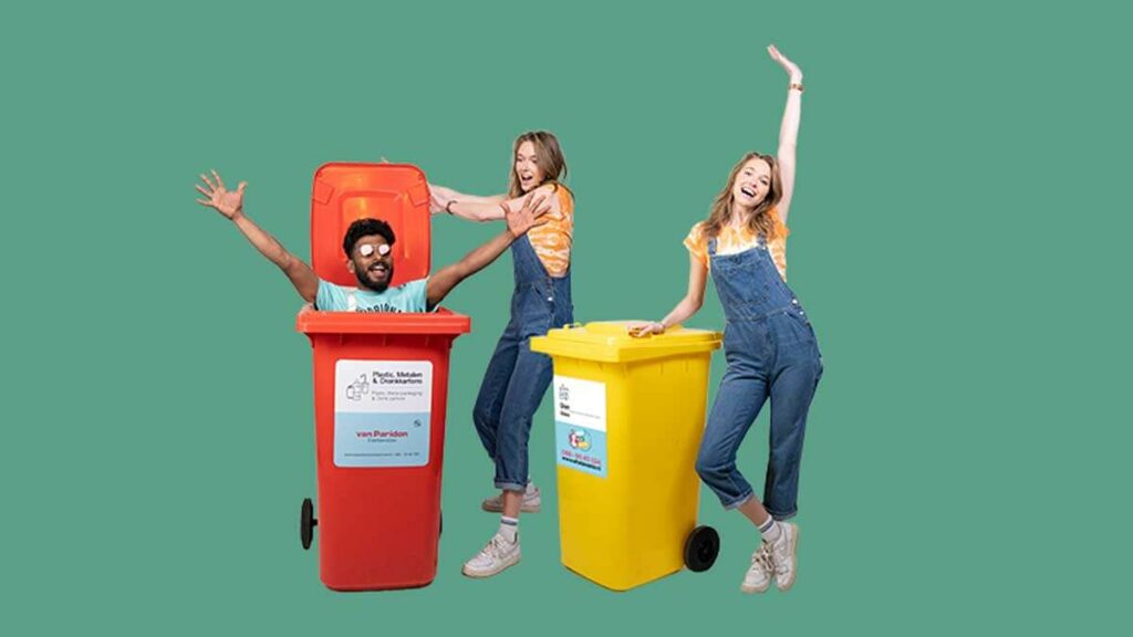 Schoonmaakteam van What A Waste met rolcontainers in groene omgeving, onderdeel van terreinreiniging en afvalbeheer evenementen.