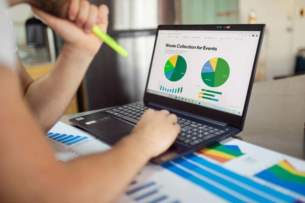 Man die afvalinzameling en rapportage analyseert op laptop met grafieken over afvalverzameling voor evenementen.