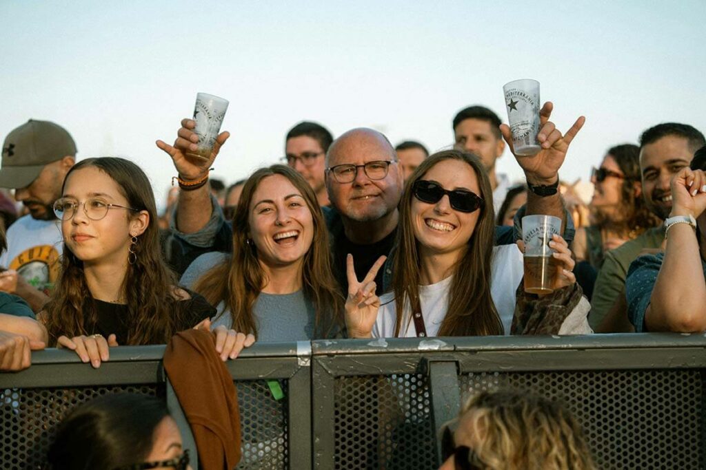 Vrolijke festivalgangers proosten met herbruikbare plastic bekers tijdens een evenement, illustratie van duurzame bekercup recycling door What A Waste.