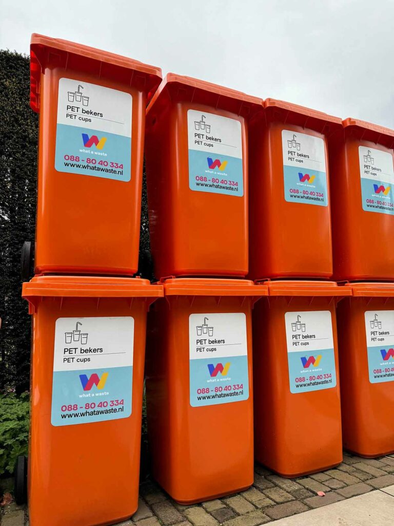 Stapel lege rolcontainers van What A Waste, klaar voor gebruik bij afvalinzameling en evenementenbeheer.