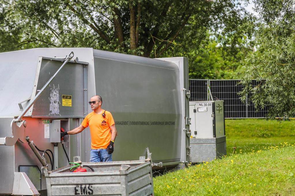 Close-up van een perscontainer met open klep, onderdeel van de afvalbeheer werkwijze van What A Waste voor evenementen.